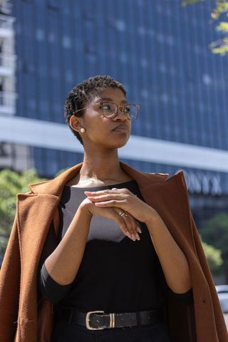 Confident african professional in glasses and brown coat on downtown street