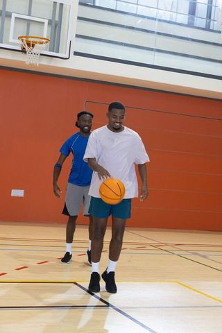 African american teammates dribbling basketball practicing teamwork on indoor court