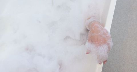 Woman's Forearm Resting on Bathtub Edge with Foam