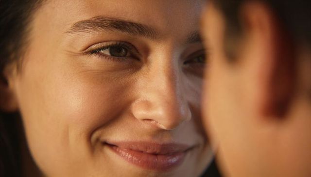 Intimate closeup smiling woman gazing at partner with warm soft light and gentle smile