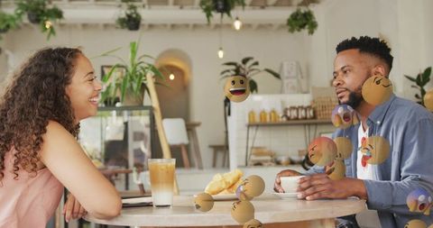 Couple sharing coffee and laughing in modern cafe with ar emoji overlays