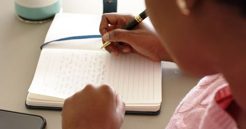 Woman Writing in Notebook at Table with Smartphone Nearby - Download Free Stock Images Pikwizard.com