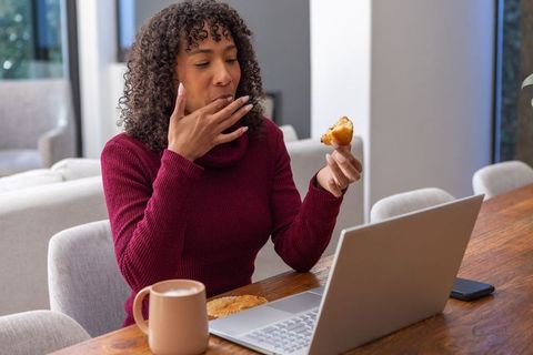 Woman Multitasking with Technology and Snack in Comfortable Setting