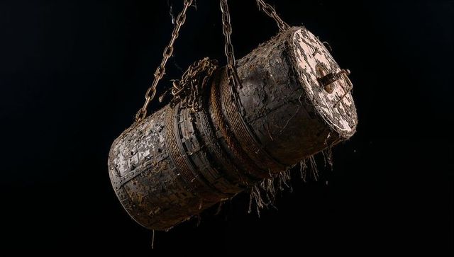 Suspended corroded metal drum with rusted chains frayed rope and peeling paint texture