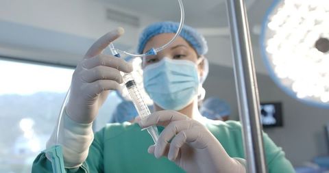 Female Surgeon Preparing IV in Operating Room