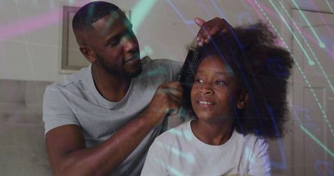 Black father combing daughter afro hair on couch while bonding with gentle home haircare