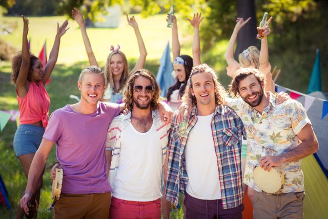 Group of friends enjoying a sunny day at a campsite, celebrating and having fun together. Ideal for use in advertisements, social media posts, and articles related to outdoor activities, friendship, and summer events.