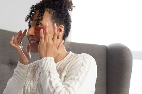 African american woman applying red under-eye gel patches for glowing skincare ritual