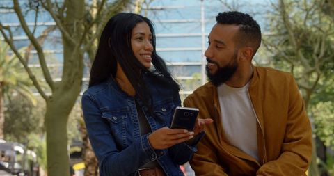Smiling Couple Sharing Smartphone Content Outdoors, Casual Attire