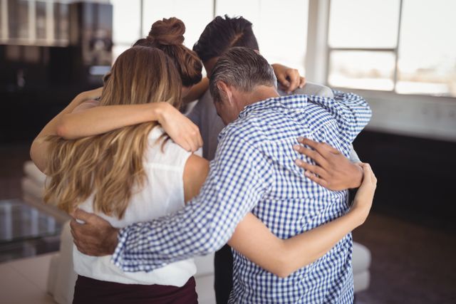 Business team huddling together in a creative office, showing unity and support. Ideal for illustrating concepts of teamwork, collaboration, and corporate culture. Useful for business presentations, team-building workshops, and motivational materials.