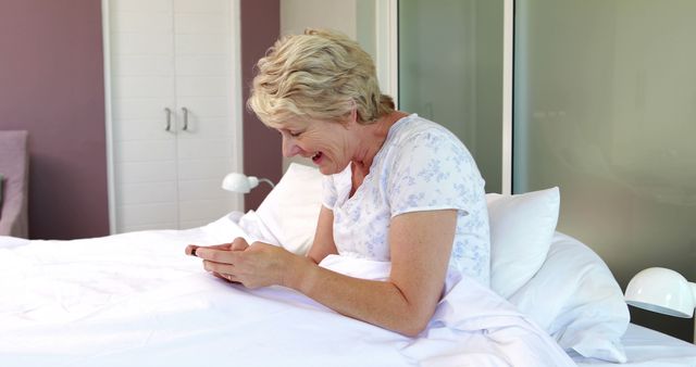 Senior Woman Laughing While Using Smartphone in Bed - Download Free Stock Images Pikwizard.com