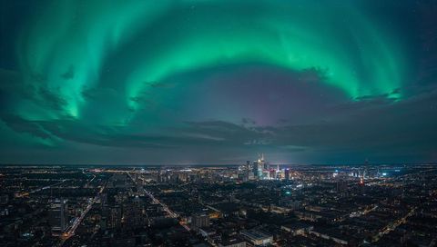 Northern Lights Arcing Over City Skyline Illuminating Downtown Skyscrapers and Streets