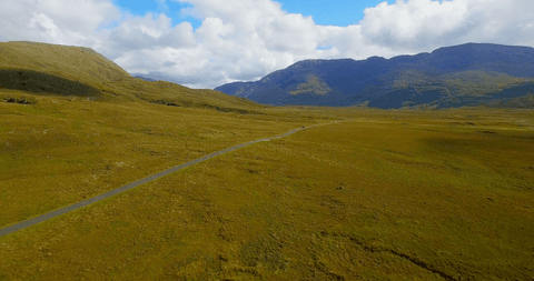 Transparent road cutting through vast rolling green mountains