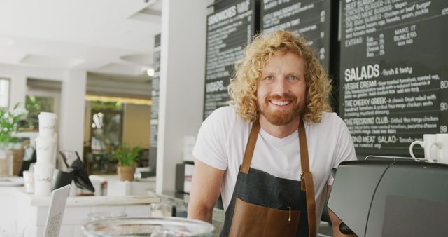 Portrait of happy caucasian male barista smiling behind the counter in cafe. Local business owner and hospitality concept.