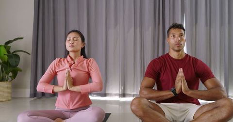 Couple Practicing Meditation and Yoga at Home Holding Prayer Pose for Wellness