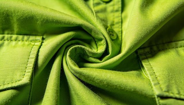 Lime green shirt front spiraling macro showing placket button pocket texture weave fibers pilling