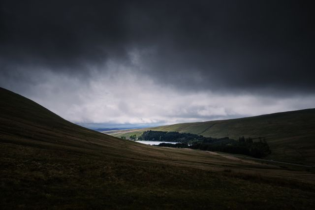 Dramatic Dark Sky Over Rolling Hills and Forest Near Small Lake - Download Free Stock Photos Pikwizard.com