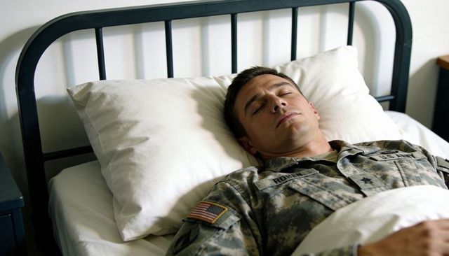 Us army soldier resting on barracks bed wearing camouflage uniform with flag patch