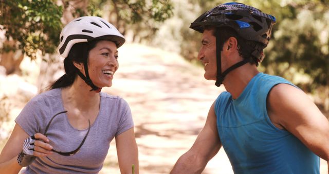 Smiling young couple riding bicycle in forest