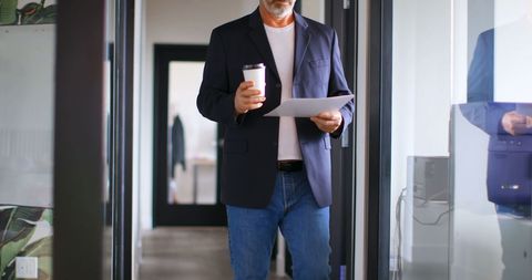 Businessman Reviewing Documents in Modern Office Hallway