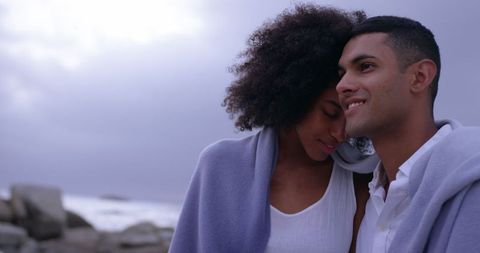 Romantic Biracial Couple Embracing on Beach with Blanket