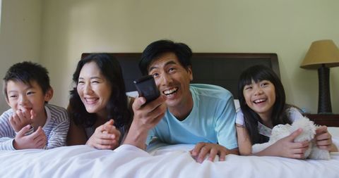 Happy Asian Family Relaxing on Bed Watching Smartphone Together - Download Free Stock Images Pikwizard.com