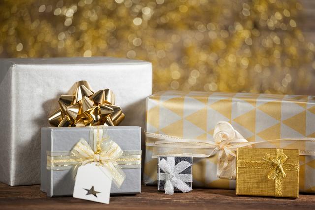 This image showcases beautifully wrapped gift boxes with golden decorations, perfect for the Christmas holiday season. The elegant wrapping and festive ribbons make it ideal for use in holiday marketing materials, greeting cards, or social media posts celebrating special occasions and gift-giving.