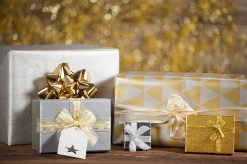 This image showcases beautifully wrapped gift boxes with golden decorations, perfect for the Christmas holiday season. The elegant wrapping and festive ribbons make it ideal for use in holiday marketing materials, greeting cards, or social media posts celebrating special occasions and gift-giving.