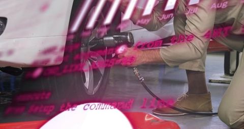 Khaki-clad mechanic tightening lug nuts with impact wrench in bay with magenta overlay