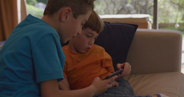 Two Boys Playing on Smartphone While Sitting on Couch at Home - Download Free Stock Images Pikwizard.com