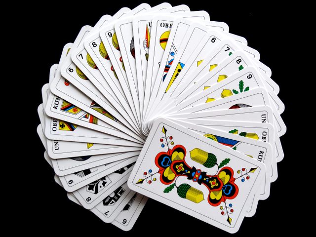 Italian playing cards neatly fanned out against a black background, showcasing various vibrant patterns and numbers. Perfect for themes related to poker, casino games, hobbies, strategies, and cultural activities. Ideal for representing the joy of card games, illustrating blog posts about playing card history, or adding a gambling theme to graphic designs.