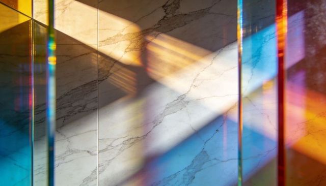 Prism light casting diagonal rainbow across polished marble wall with glass panels