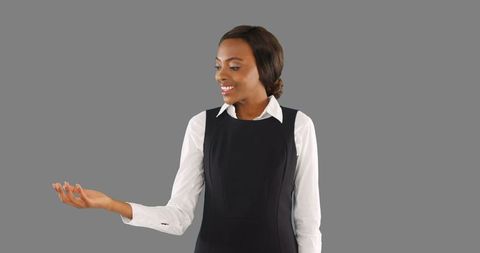 Smart businesswoman observing object in hand against grey background