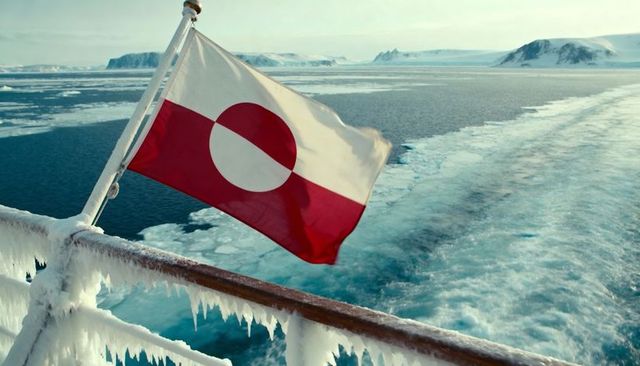 Greenland flag waving over frost-covered ship rail with icicles and arctic ice floes