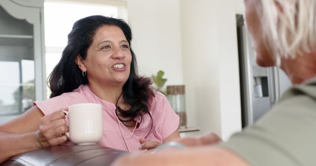 Middle-aged woman laughing and drinking coffee in conversation - Download Free Stock Images Pikwizard.com