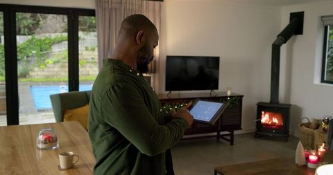 African American Man Using Smart Home Tablet in Cozy Modern Living Room with Fireplace
