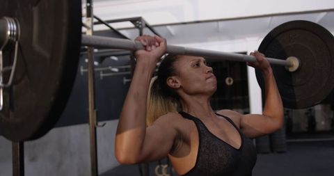 Athletic woman lifting barbell in modern gym