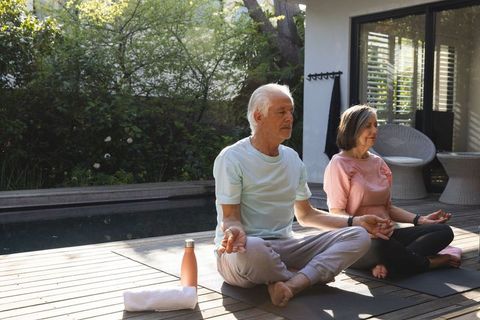 Senior Couple Meditating by Pool in Tranquil Outdoor Setting