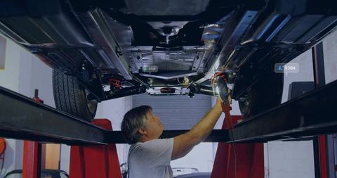 Mechanic inspecting car undercarriage on garage lift