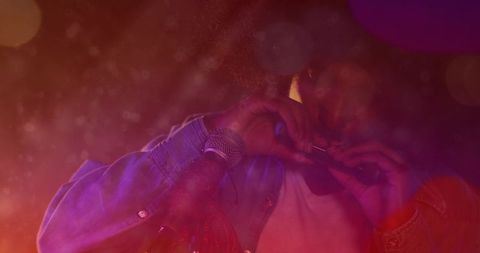 Indian Male Musician Playing Harmonica on Dim Concert Stage with Microphone, Haze, Bokeh