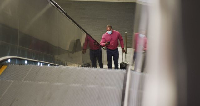 Traveler Using Phone on Escalator at Airport Terminal Wearing Face Mask - Download Free Stock Images Pikwizard.com