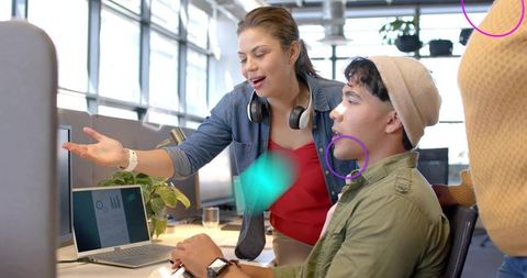 Young professionals collaborating over laptop in modern open-plan office, startup teamwork