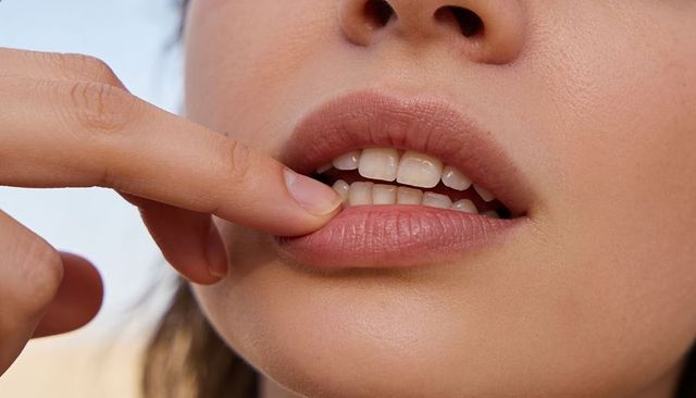 Woman pressing lower lip to reveal front teeth close-up portrait showing skin texture