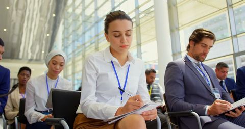 Focused Diverse Professionals in Business Seminar Taking Notes