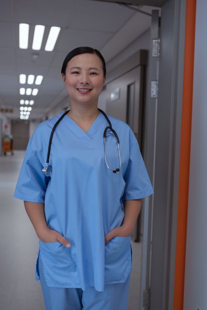 Front view of female doctor with hands on pocket standing in corridor at hospital