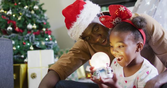 Father and daughter celebrating Christmas with snow globe - Download Free Stock Images Pikwizard.com