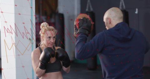 Female boxer training with coach in gym with determination