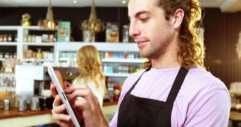 Happy Barista Using Tablet in Trendy Cafe Interior