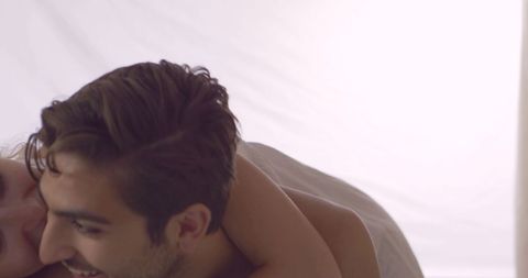 Young Couple Embracing Playfully in Bright Bedroom