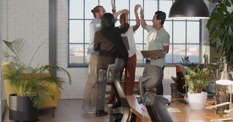 Diverse business team celebrates achievement in modern office
